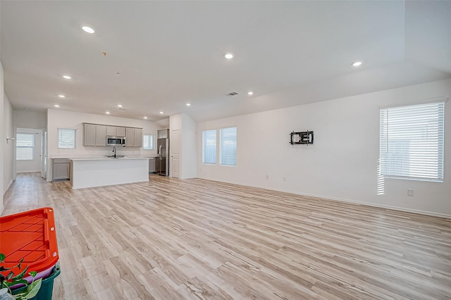 unfurnished living room with light hardwood / wood-style flooring, a wealth of natural light, and sink