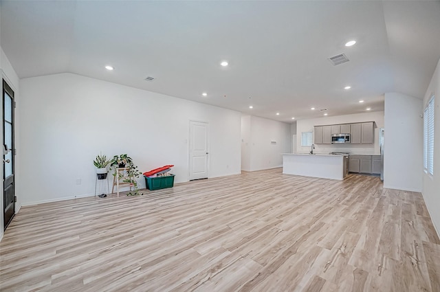 unfurnished living room featuring lofted ceiling and light wood-type flooring