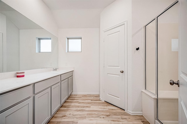 bathroom with hardwood / wood-style floors, vanity, and a shower with door