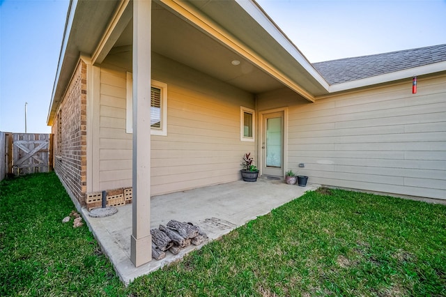 view of exterior entry with a yard and a patio area