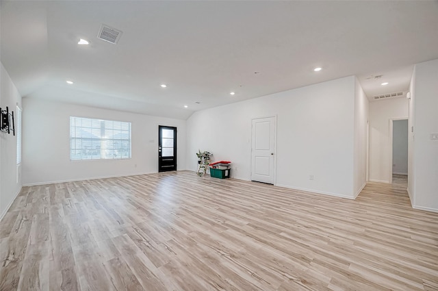 empty room with vaulted ceiling and light hardwood / wood-style flooring