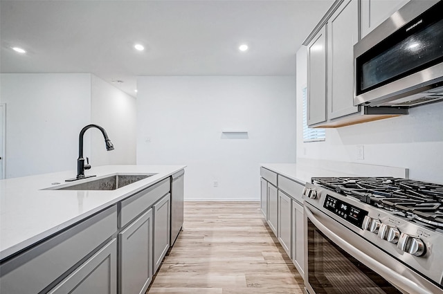 kitchen featuring gray cabinetry, sink, light wood-type flooring, and stainless steel appliances