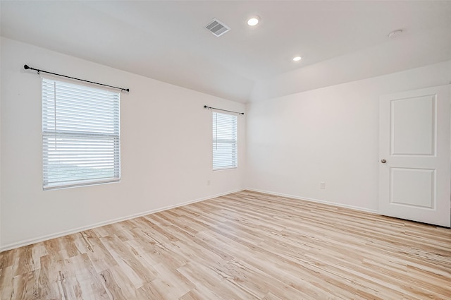 empty room featuring light hardwood / wood-style floors and vaulted ceiling