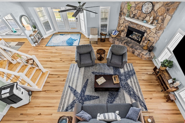 living room with hardwood / wood-style floors, ceiling fan, and a stone fireplace