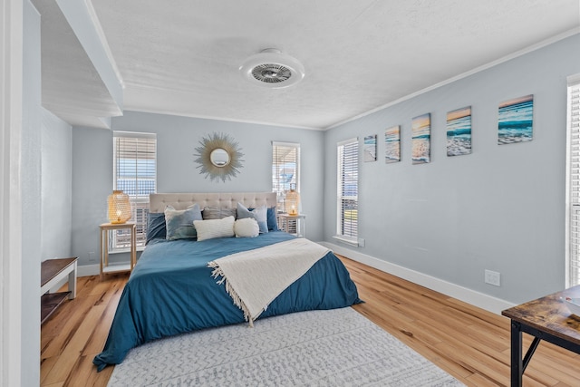 bedroom with multiple windows, wood-type flooring, a textured ceiling, and ornamental molding