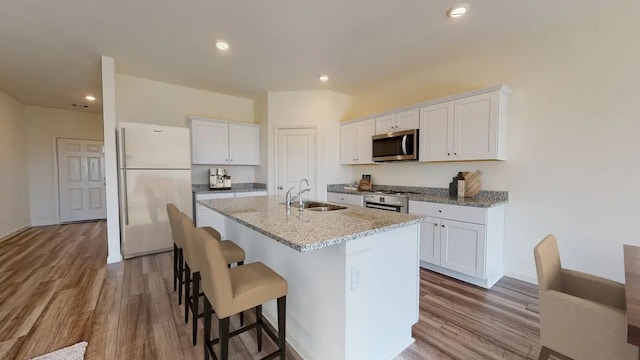 kitchen with white cabinets, sink, appliances with stainless steel finishes, and an island with sink