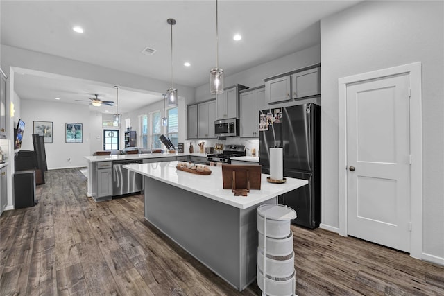 kitchen with kitchen peninsula, appliances with stainless steel finishes, a kitchen island, and ceiling fan