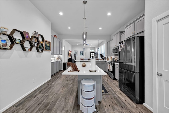 kitchen with a breakfast bar, stainless steel appliances, pendant lighting, gray cabinets, and a kitchen island