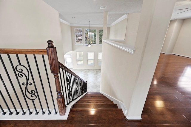 stairs with hardwood / wood-style flooring, ornamental molding, ceiling fan, and a towering ceiling