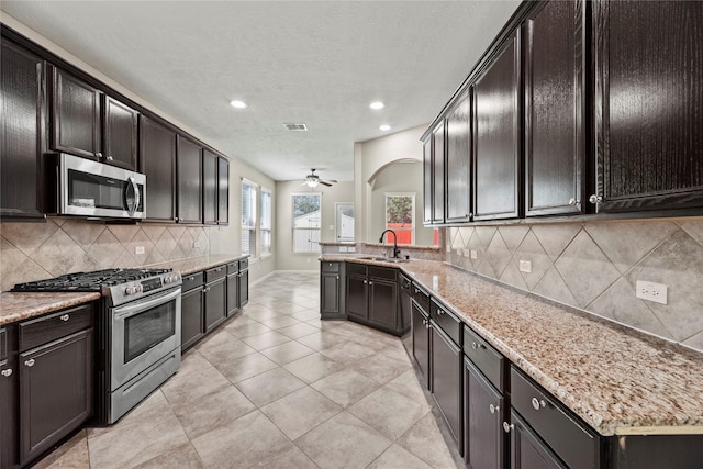 kitchen featuring sink, light tile patterned floors, appliances with stainless steel finishes, light stone countertops, and backsplash