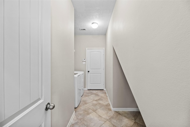 laundry area with light tile patterned floors, washing machine and clothes dryer, and a textured ceiling