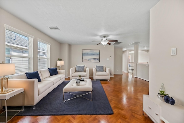 living room featuring ceiling fan, parquet flooring, and a textured ceiling