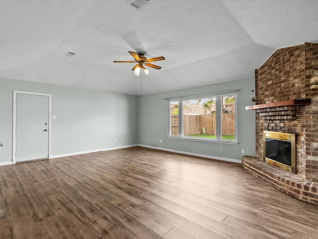 unfurnished living room featuring lofted ceiling, hardwood / wood-style flooring, ceiling fan, a fireplace, and a textured ceiling