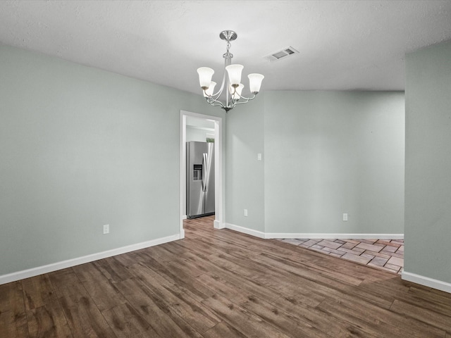 empty room with hardwood / wood-style flooring and a notable chandelier