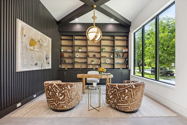 sitting room featuring built in features, beamed ceiling, and concrete flooring