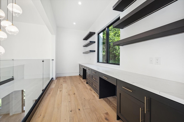 interior space with decorative light fixtures, light hardwood / wood-style floors, light stone counters, and built in desk