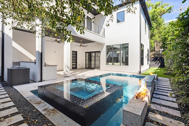 back of property with ceiling fan, a pool with hot tub, a balcony, and central air condition unit