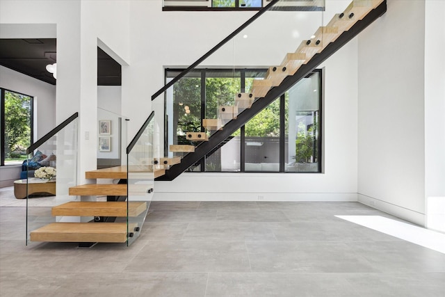 stairway with a towering ceiling and concrete floors