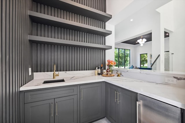 kitchen featuring gray cabinets, light stone counters, kitchen peninsula, and sink