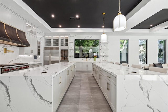 kitchen featuring stainless steel appliances, white cabinetry, a tray ceiling, and light stone counters