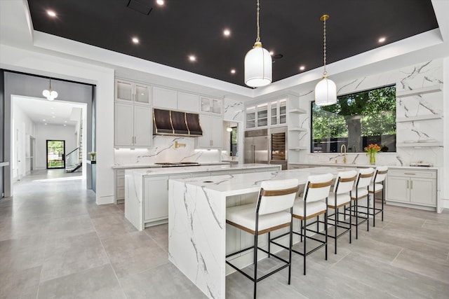 kitchen featuring tasteful backsplash, exhaust hood, white cabinetry, and a spacious island