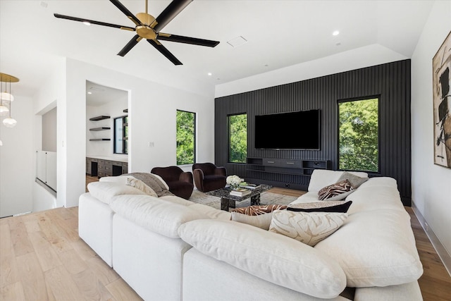 living room featuring ceiling fan, light hardwood / wood-style flooring, and vaulted ceiling