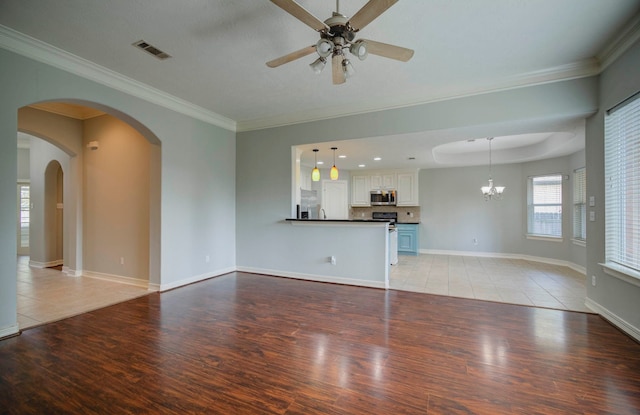 unfurnished living room with ceiling fan with notable chandelier, light wood-type flooring, and ornamental molding