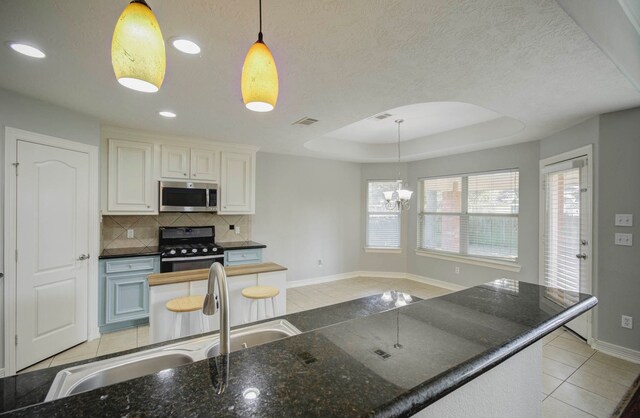 kitchen with white cabinetry, a raised ceiling, black range with gas cooktop, a chandelier, and decorative light fixtures