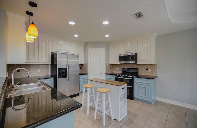 kitchen with white cabinetry, sink, light tile patterned floors, a kitchen island, and appliances with stainless steel finishes