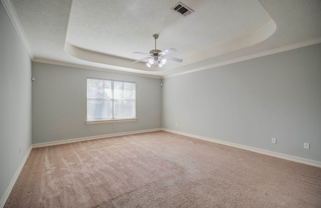 spare room featuring light carpet, ornamental molding, a textured ceiling, a tray ceiling, and ceiling fan