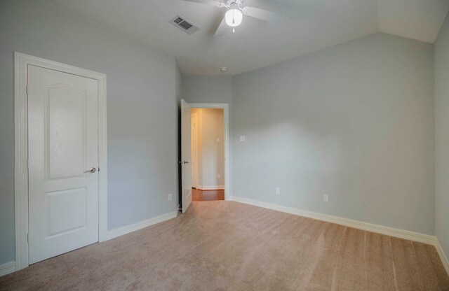 unfurnished bedroom featuring ceiling fan, light carpet, and vaulted ceiling