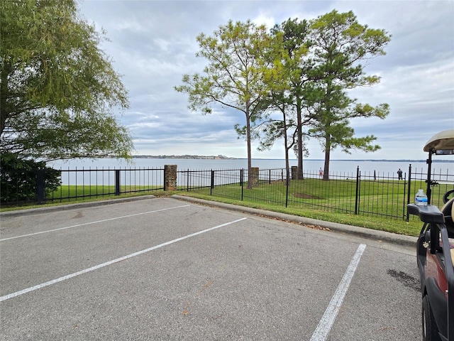 view of car parking with a water view and a yard