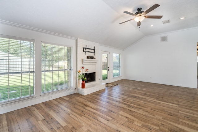 unfurnished living room with a brick fireplace, hardwood / wood-style flooring, vaulted ceiling, and ornamental molding