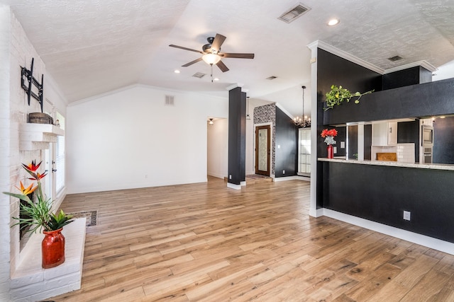 living room featuring hardwood / wood-style floors, ceiling fan with notable chandelier, vaulted ceiling, and a textured ceiling