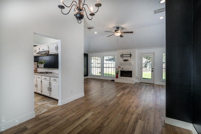 unfurnished living room featuring lofted ceiling, a brick fireplace, hardwood / wood-style flooring, and ceiling fan with notable chandelier