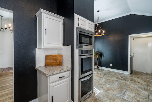 kitchen with white cabinetry, hanging light fixtures, stainless steel microwave, and an inviting chandelier