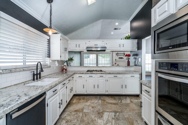 kitchen featuring vaulted ceiling, appliances with stainless steel finishes, decorative light fixtures, white cabinetry, and sink