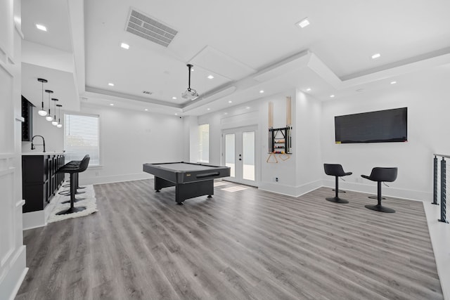 game room with hardwood / wood-style floors, a raised ceiling, a wealth of natural light, and billiards