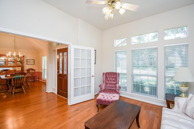 sitting room with vaulted ceiling, ceiling fan with notable chandelier, and light hardwood / wood-style flooring