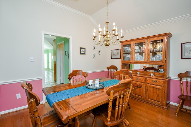 dining room featuring vaulted ceiling, an inviting chandelier, ornamental molding, and hardwood / wood-style floors