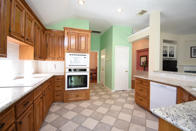 kitchen featuring vaulted ceiling, white appliances, tasteful backsplash, and light stone counters