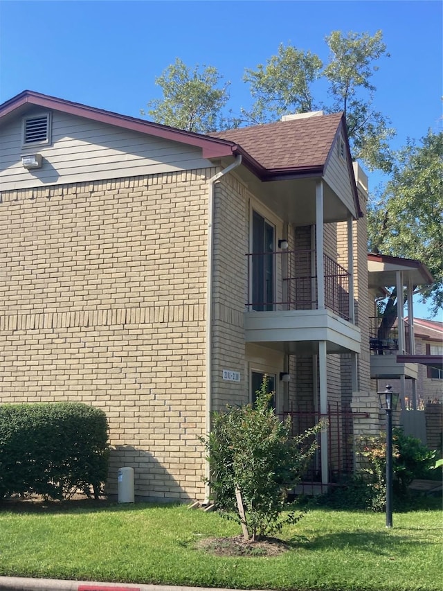 view of home's exterior featuring a balcony and a lawn