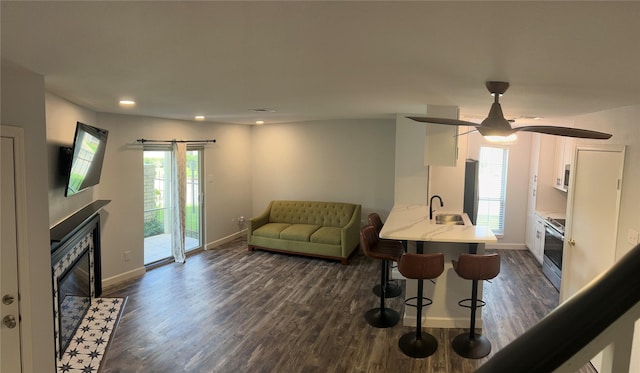 living room with ceiling fan, dark wood-type flooring, and sink