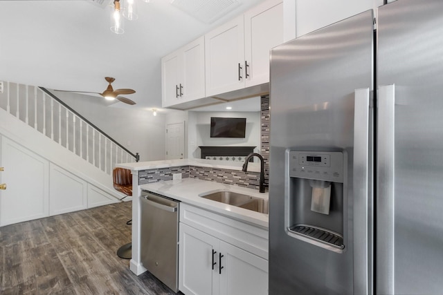 kitchen featuring a sink, light countertops, backsplash, appliances with stainless steel finishes, and dark wood-type flooring