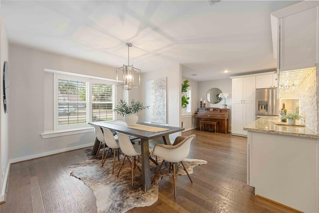 dining area with hardwood / wood-style floors and an inviting chandelier