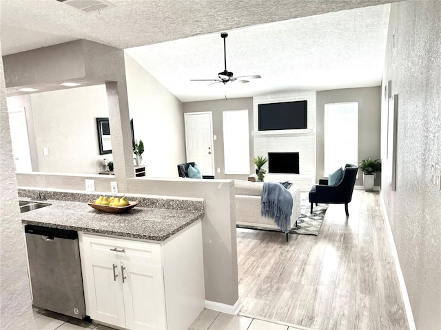 kitchen with dishwasher, white cabinets, ceiling fan, a textured ceiling, and stone countertops