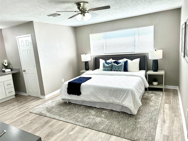 bedroom with a textured ceiling, light wood-type flooring, and ceiling fan