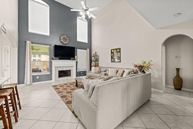 living room featuring ceiling fan, light tile patterned flooring, a tile fireplace, and high vaulted ceiling