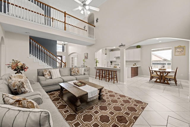 tiled living room with ceiling fan, plenty of natural light, and a towering ceiling