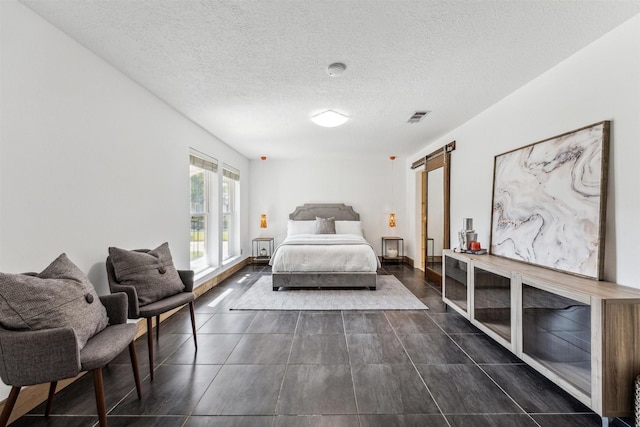 bedroom featuring a textured ceiling and a barn door